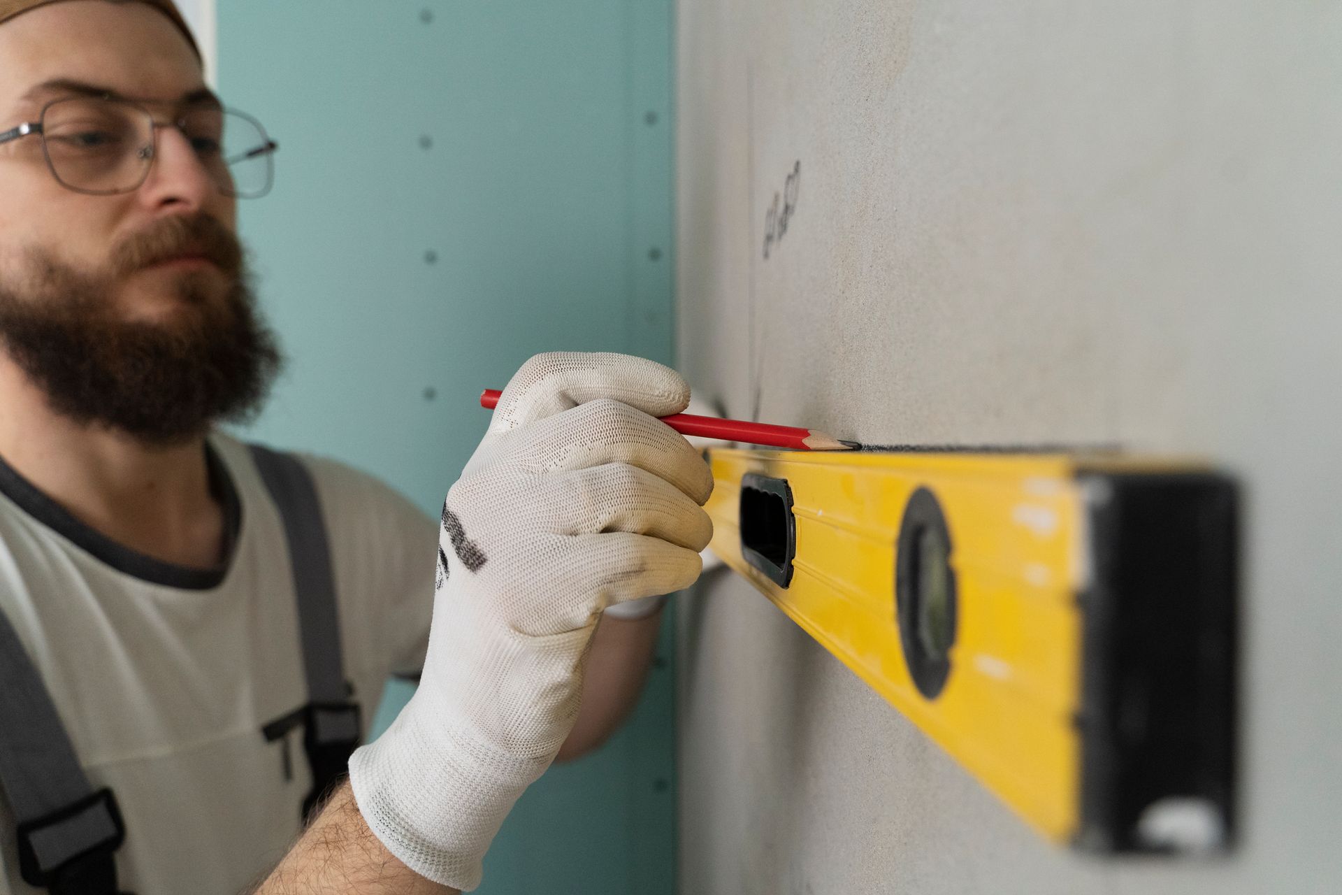 A man with a beard is measuring a wall with a level.
