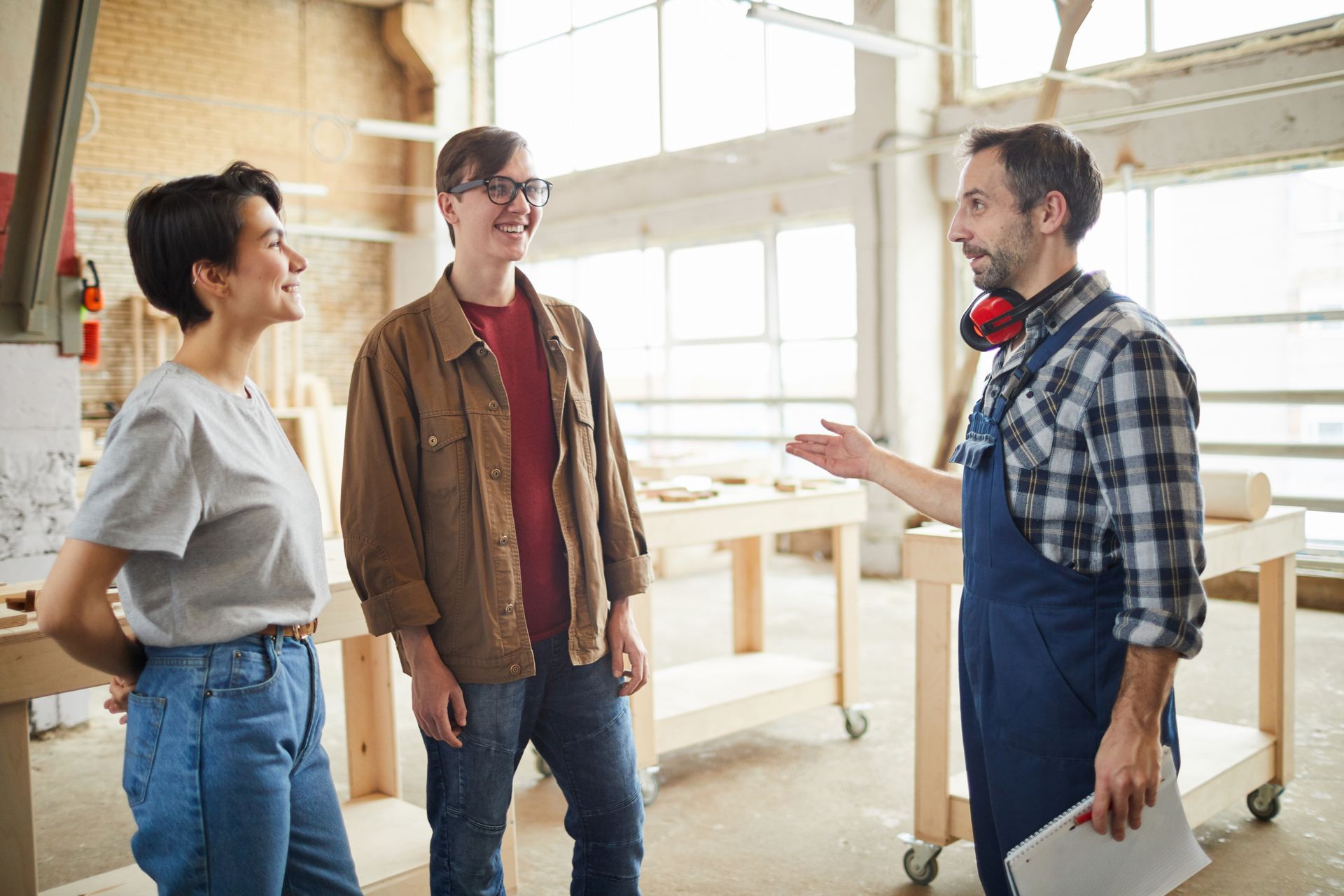 A man is talking to a woman and a man in a workshop.