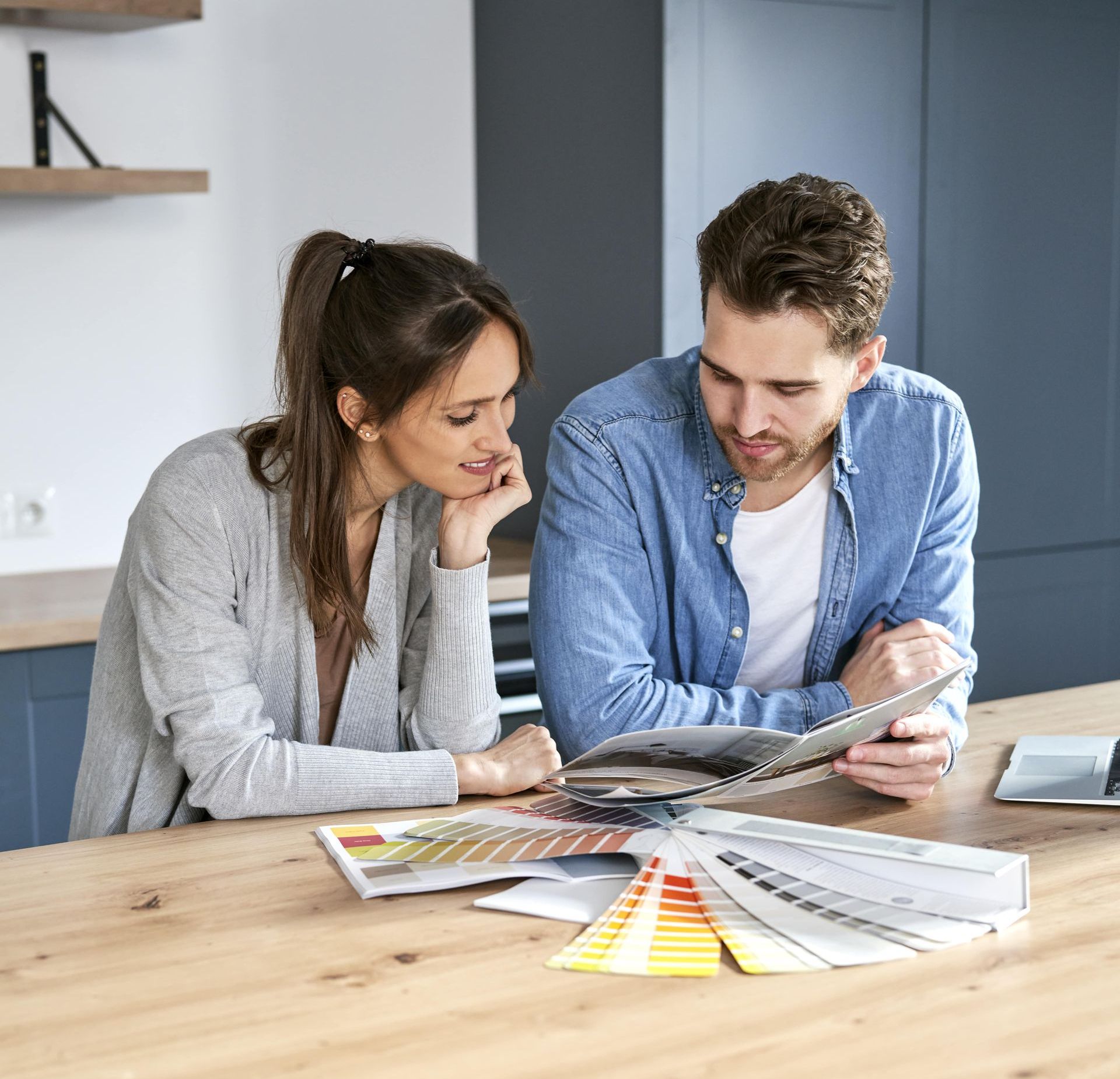 A man and a woman are sitting at a table looking at a book.