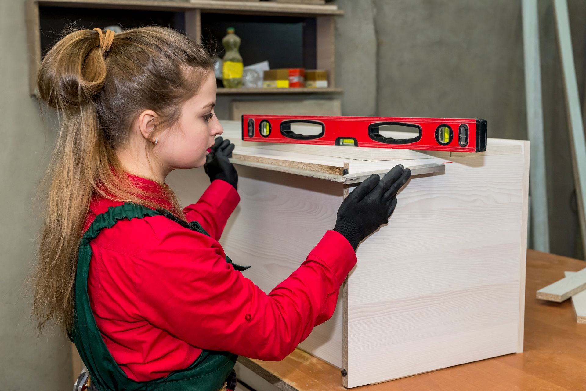 A woman is using a level to check the level of a piece of wood.