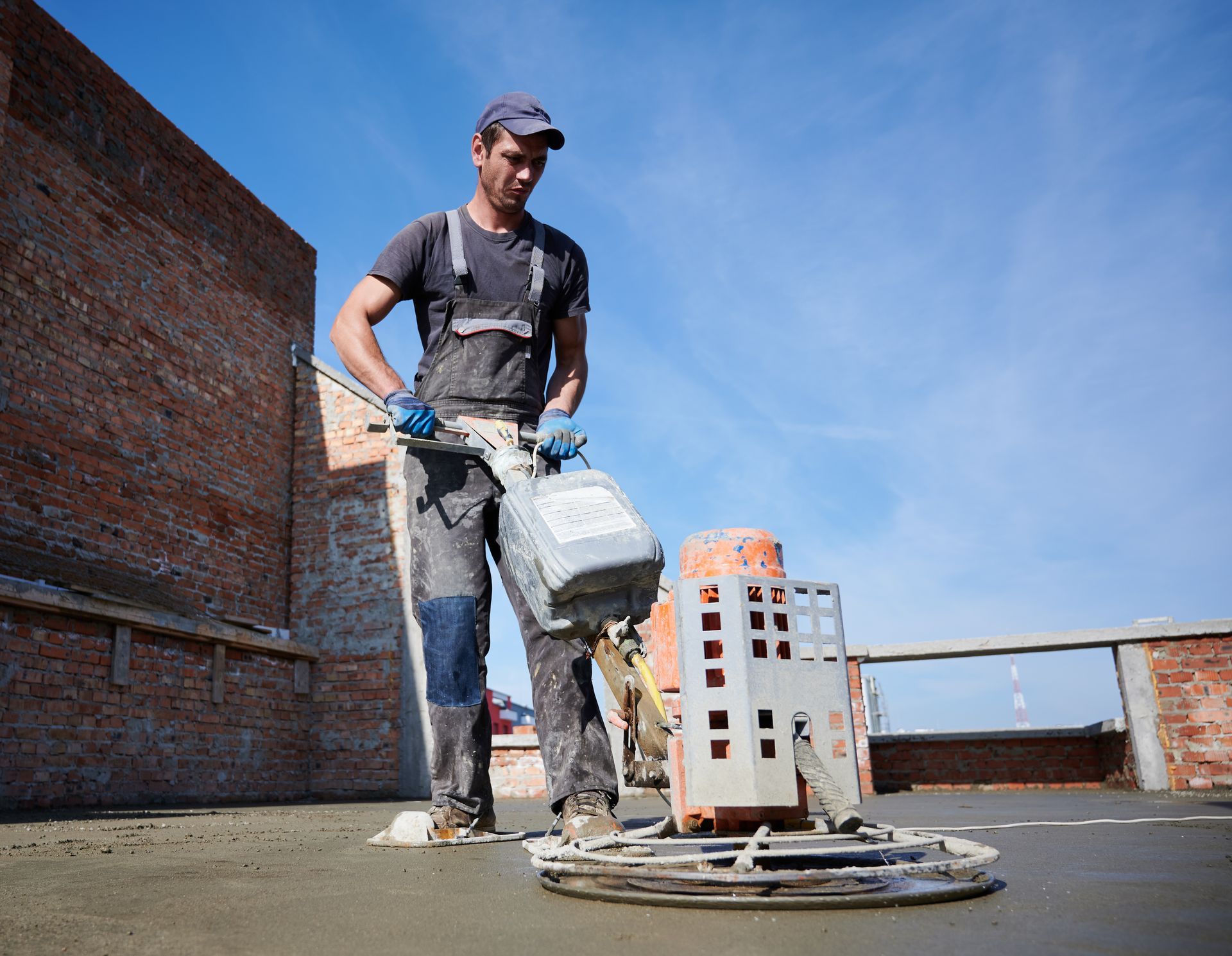 A man is using a machine to finish a concrete floor.