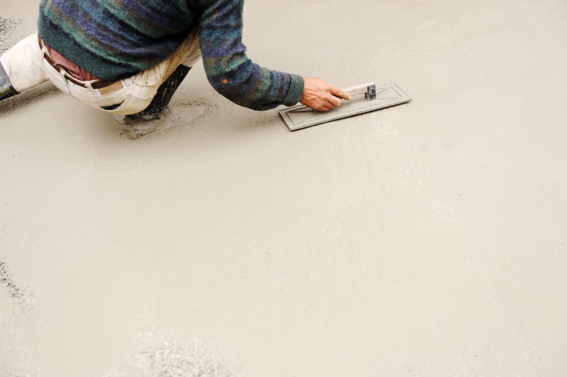 A man is troweling concrete on the floor.