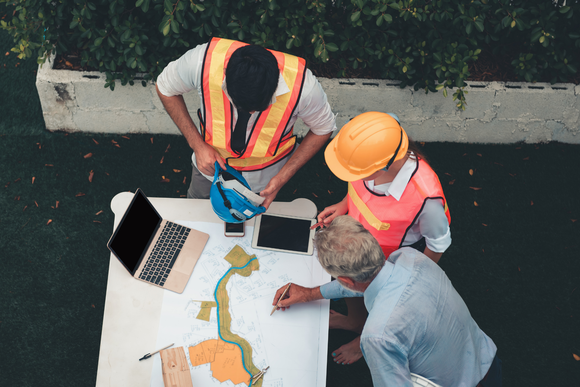 A group of construction workers are sitting around a table looking at a blueprint.