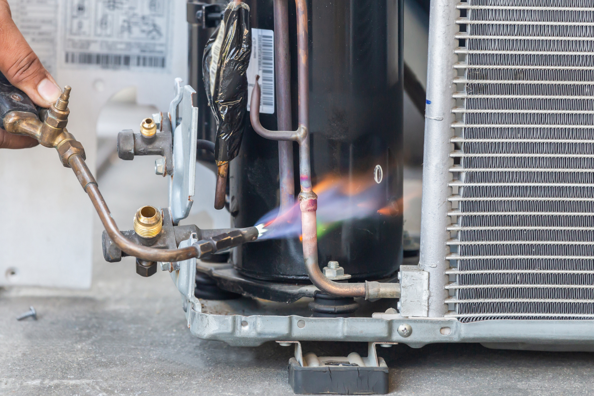 A person is using a torch to fix an air conditioner.