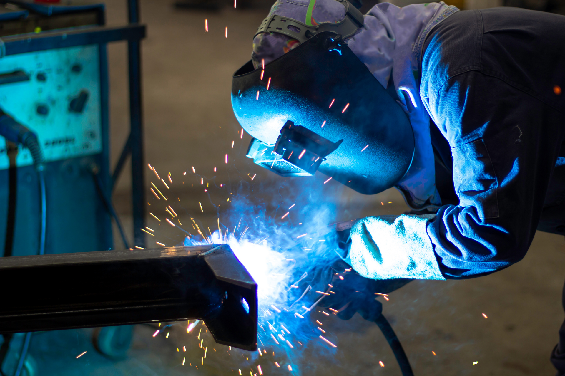 A man is welding a piece of metal in a factory.