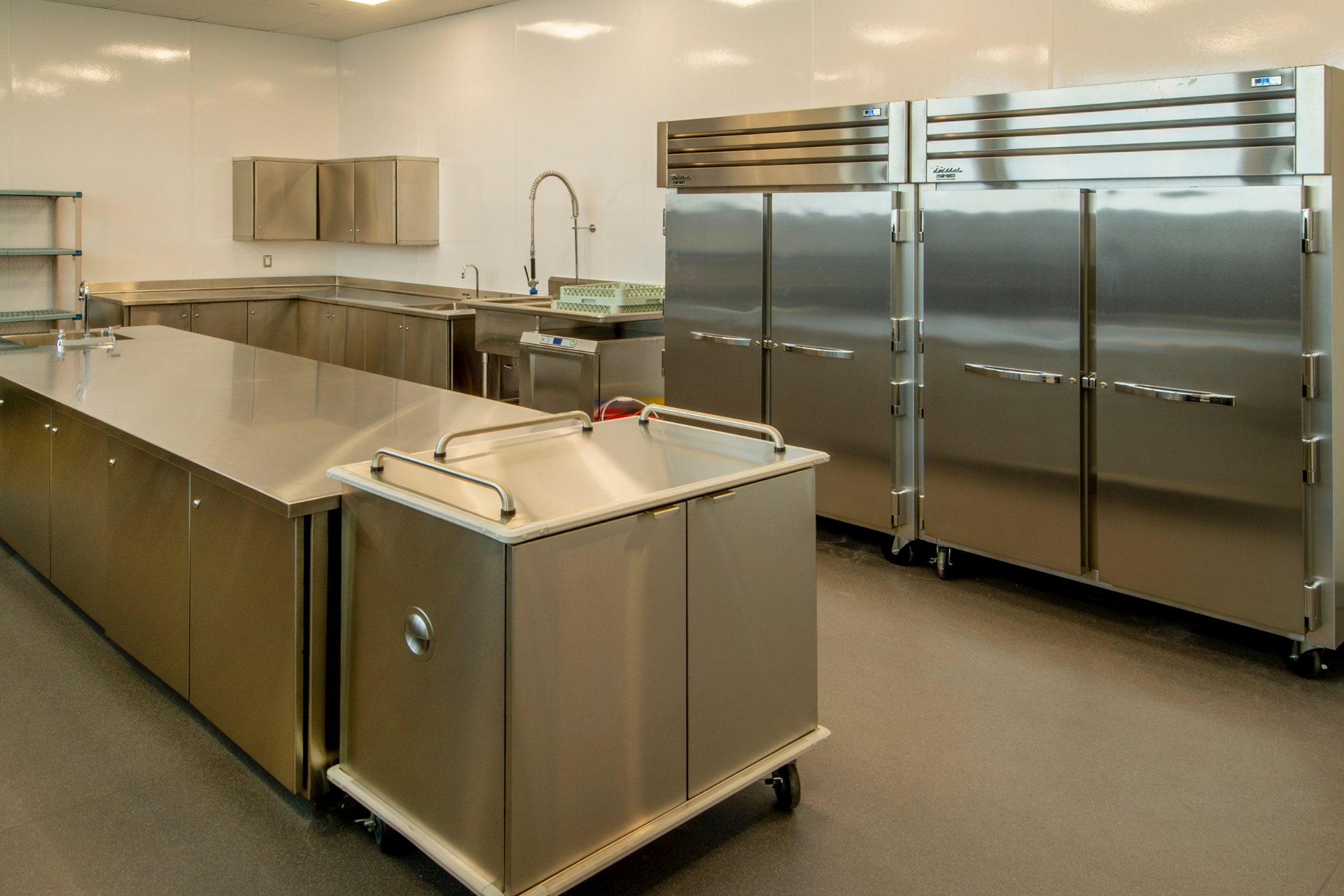 A kitchen with stainless steel appliances and a cart