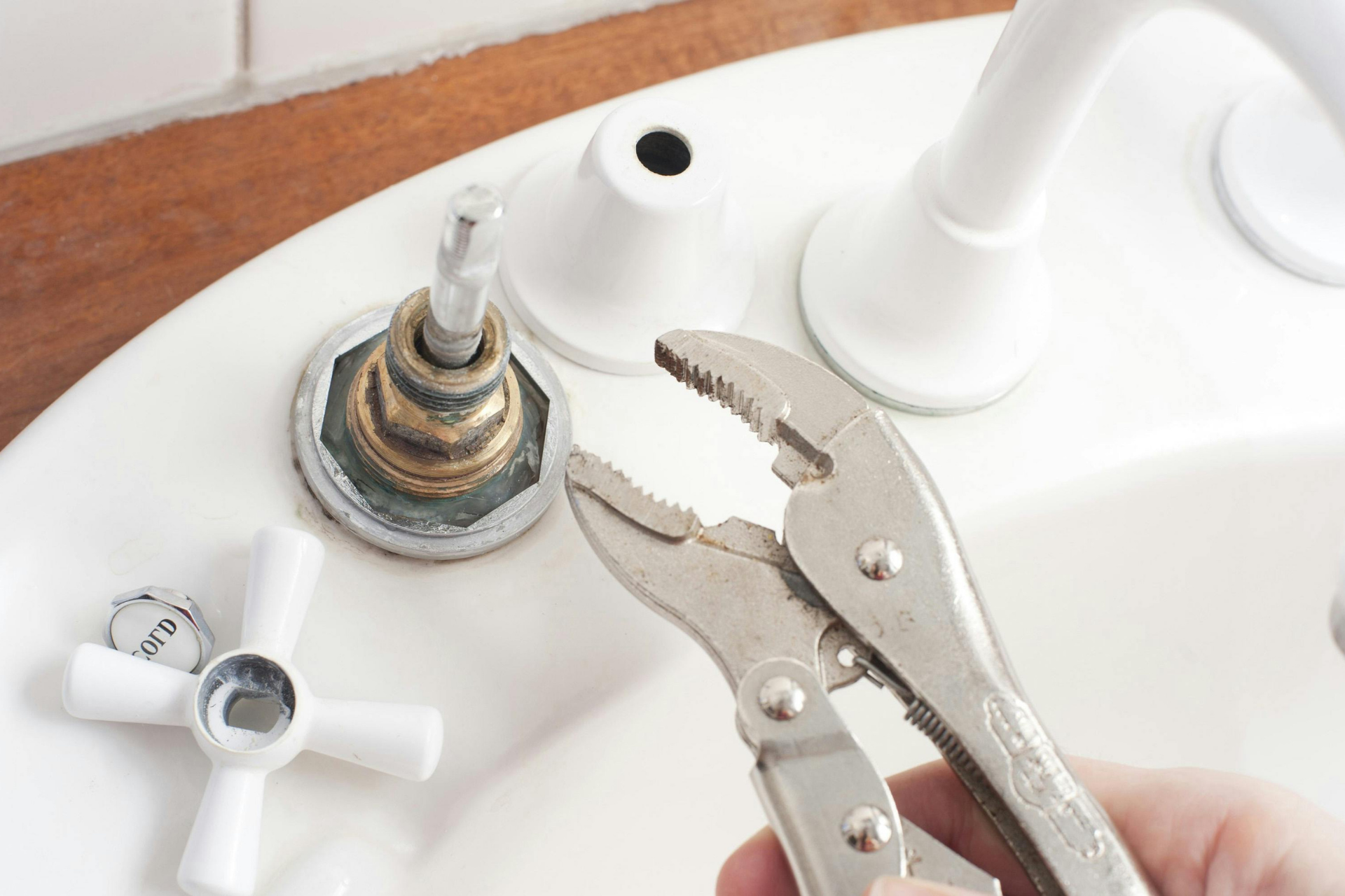 A person is fixing a sink with a wrench.