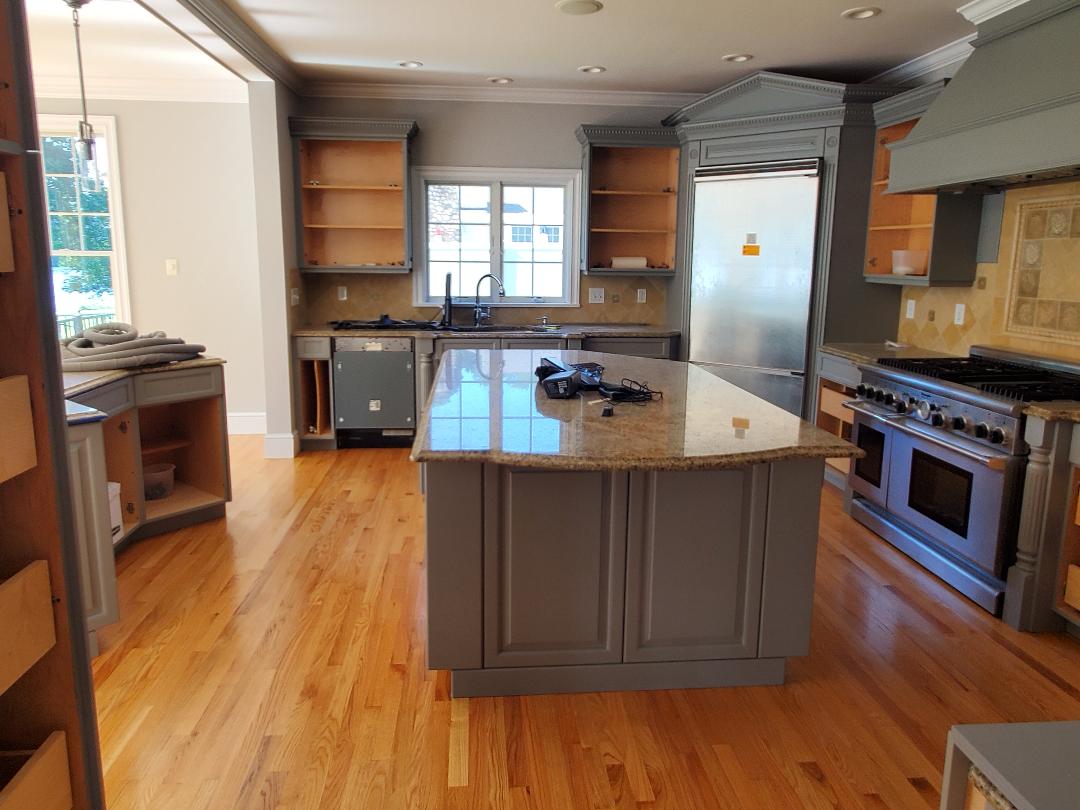 Kitchen remodel: grey cabinets, island, stainless steel appliances, hardwood floors.