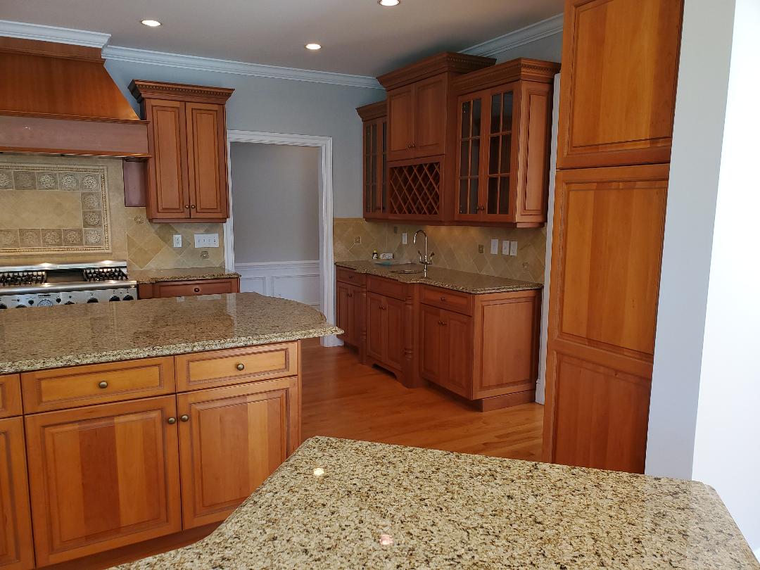 Wooden kitchen with granite countertops, cabinets, and a range.
