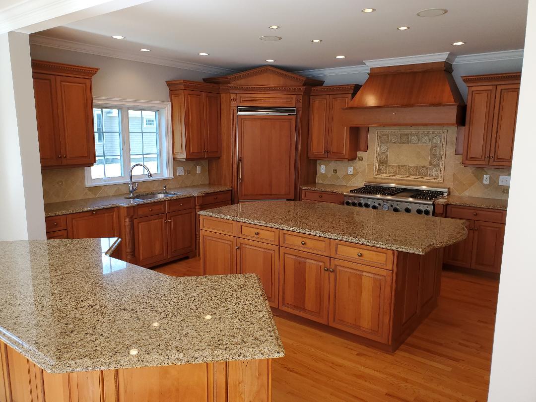 A spacious kitchen with wooden cabinets, granite countertops, and a large island.