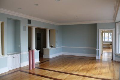 Spacious room with light blue walls, white trim, wooden floor, and two pink yoga mats.
