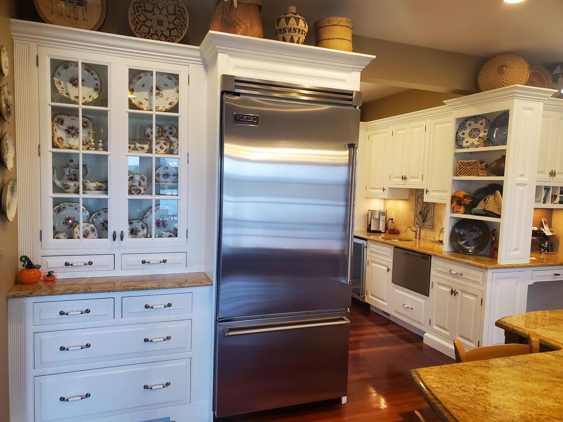 Kitchen with white cabinets, stainless steel refrigerator, and decorative plates on display.