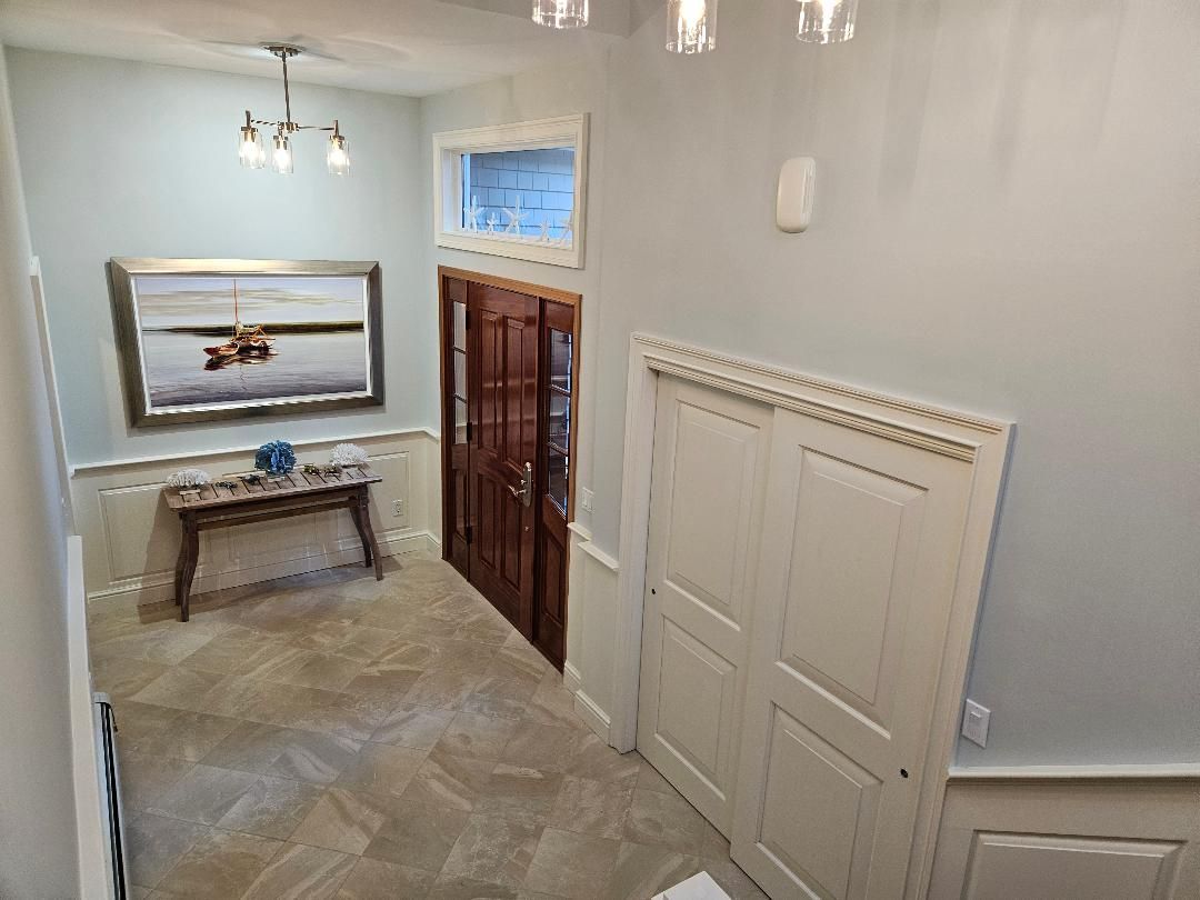 Entryway with a wooden door, art, console table, light fixture, and white trim.