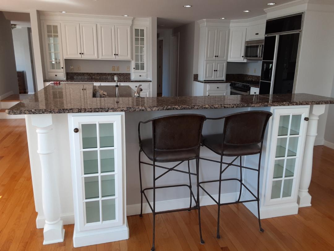 Kitchen with white cabinets, granite countertops, and two bar stools.