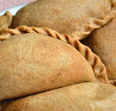 Primer plano de pasteles horneados de color marrón dorado y con los bordes ondulados, apilados uno sobre otro.