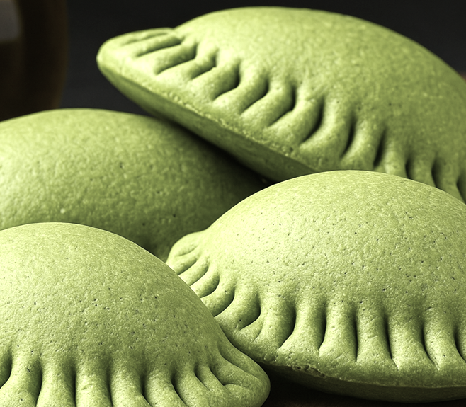 Cuatro pasteles verdes y ondulados, apilados sobre un fondo oscuro.