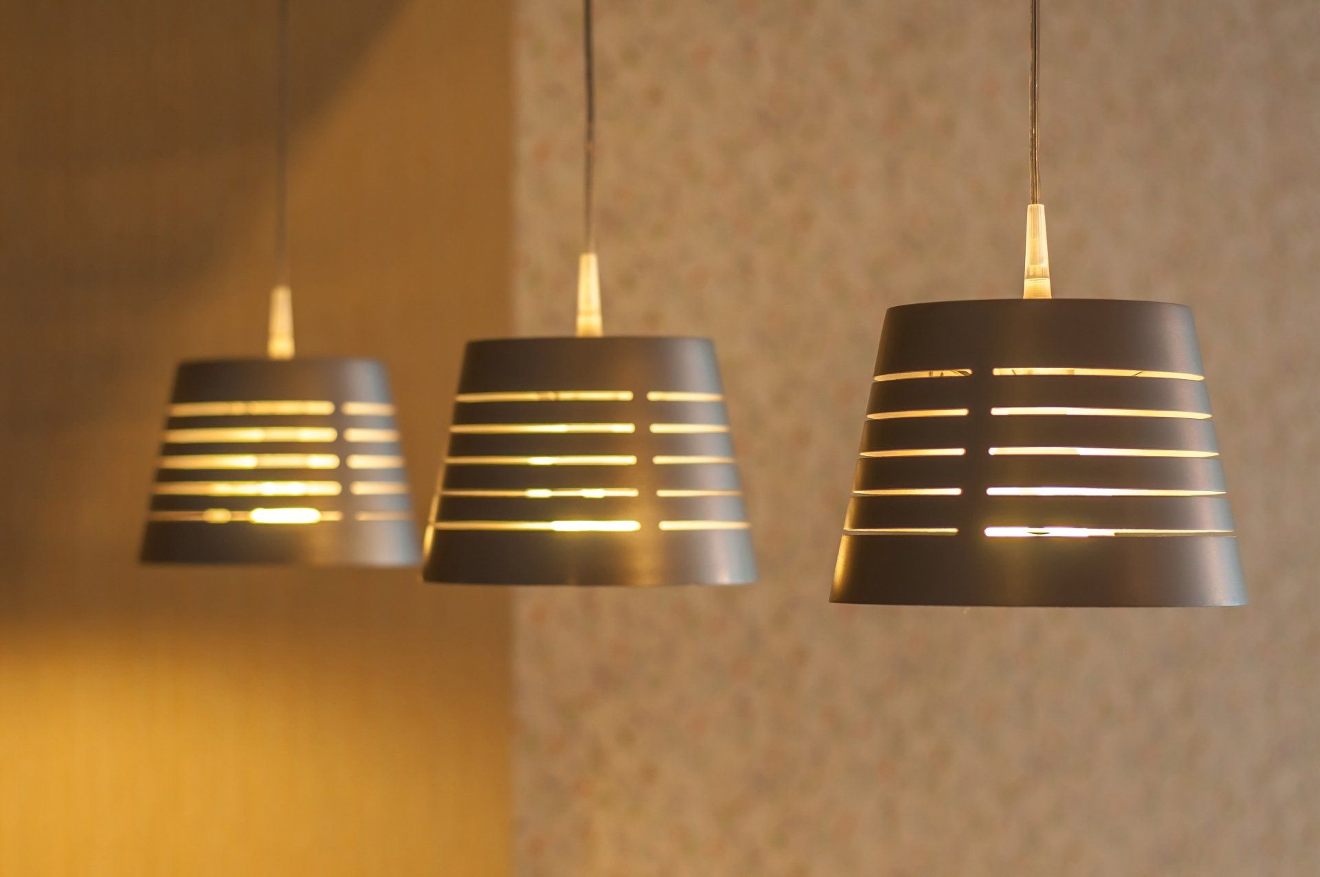 Three lamps are hanging from the ceiling and one has a striped shade