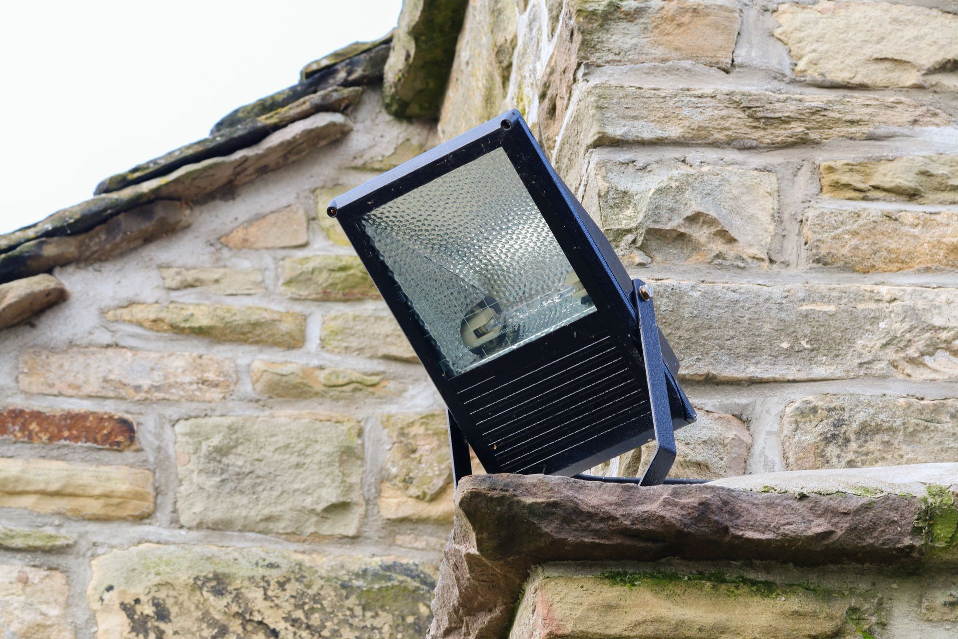 A black light is sitting on the side of a stone building.