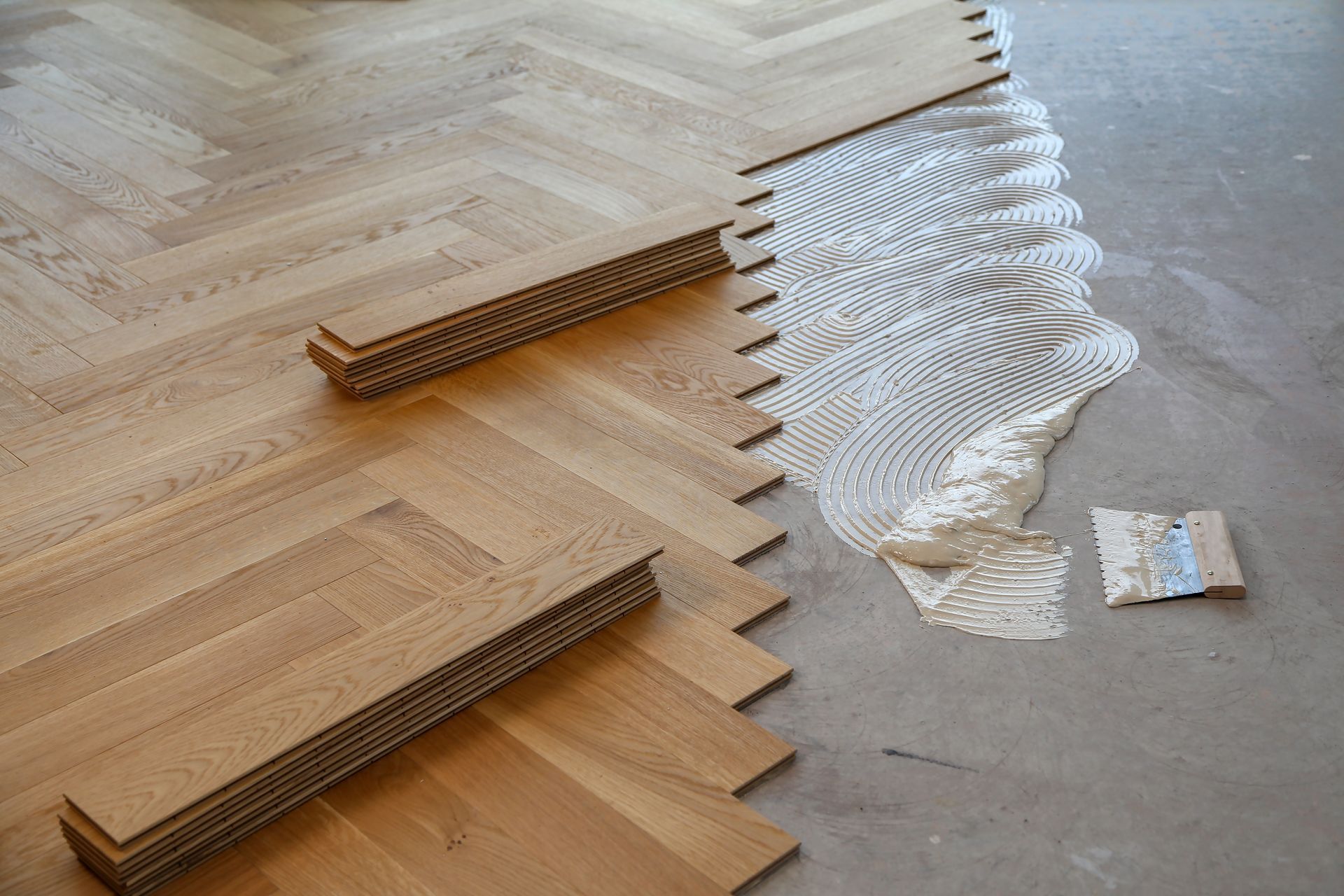 Wooden floor with accordion-fold paper sculptures and a white spiral installation on a concrete surface