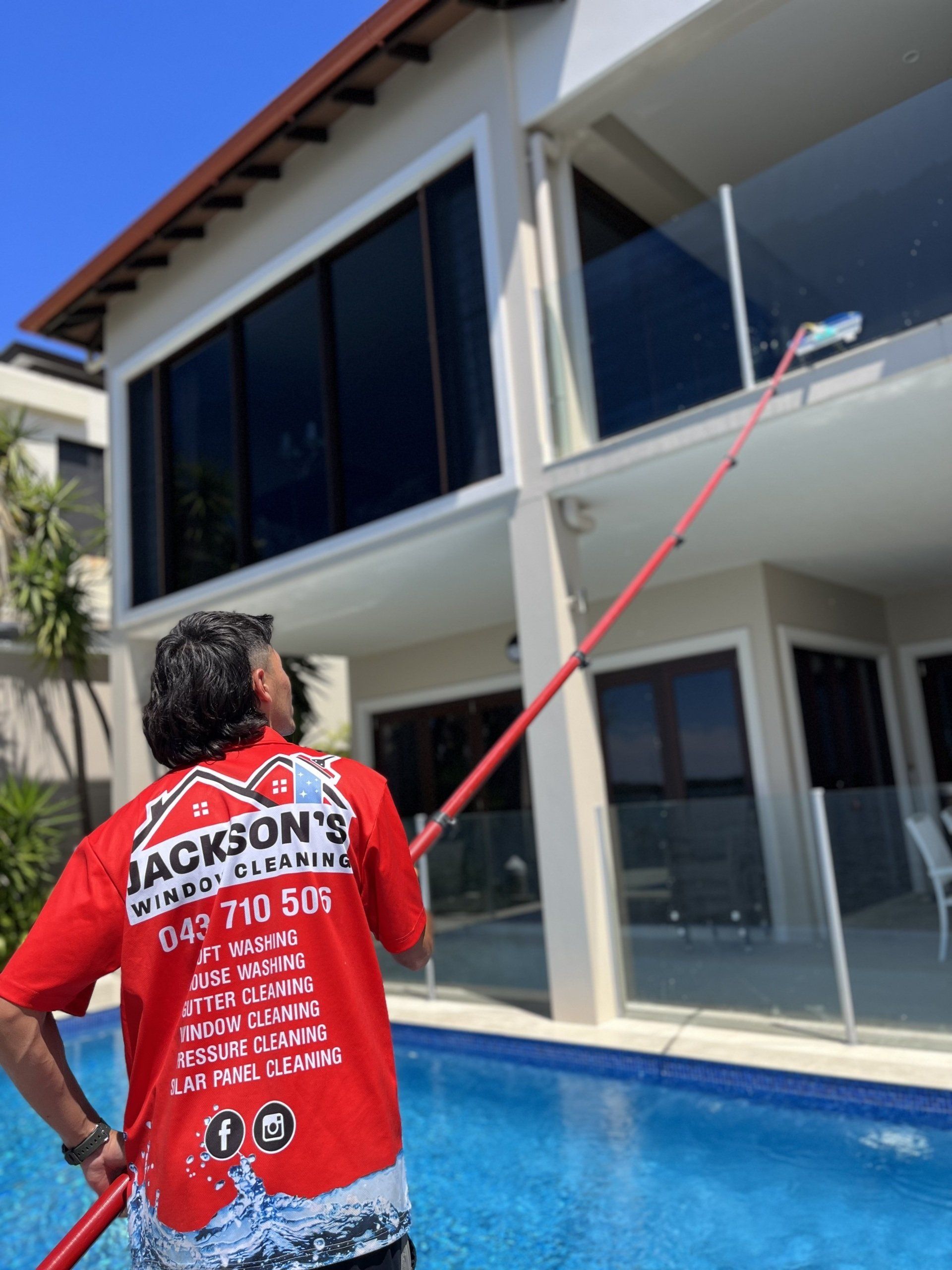 Worker Cleaning Windows by the Pool Area — Jackson’s Window Cleaning in Nerang, QLD