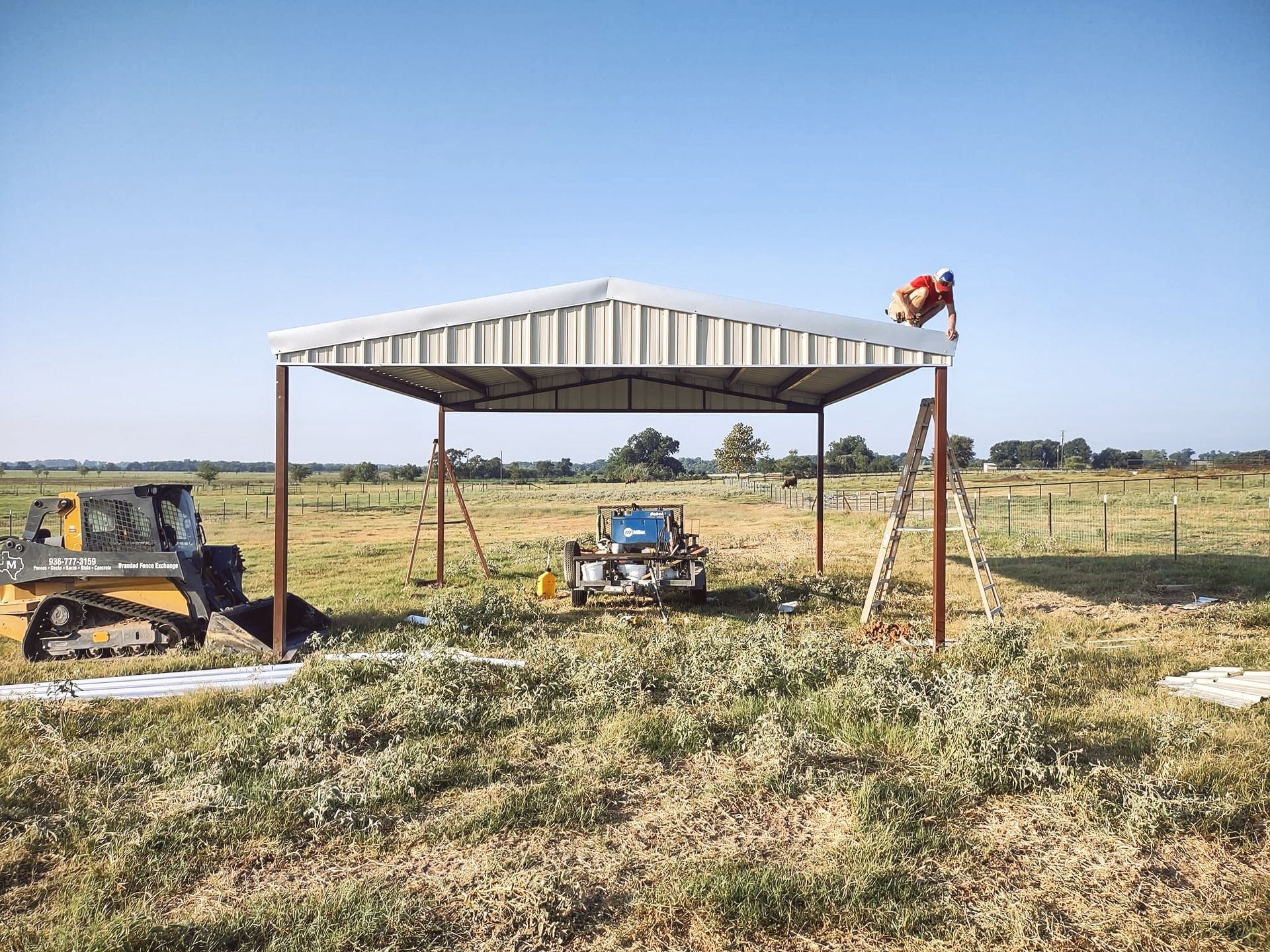 A man is working on a metal structure in a field.