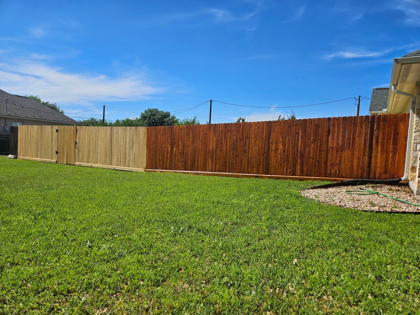 A wooden fence is sitting in the middle of a lush green yard.