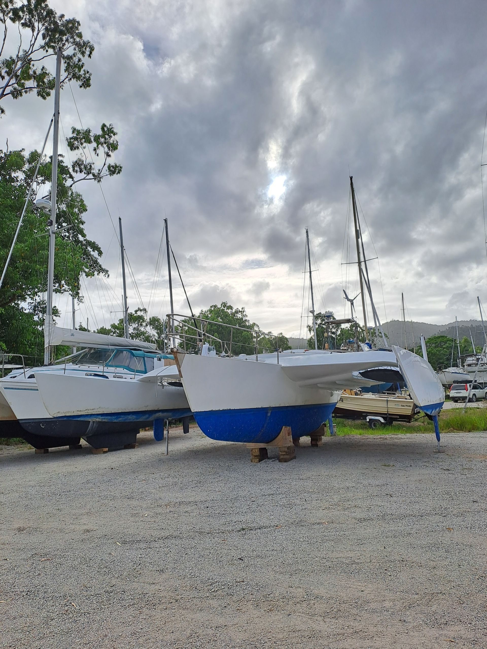 A row of boats are parked in a gravel lot — Edge's Boatyard In Jubilee Pocket, QLD