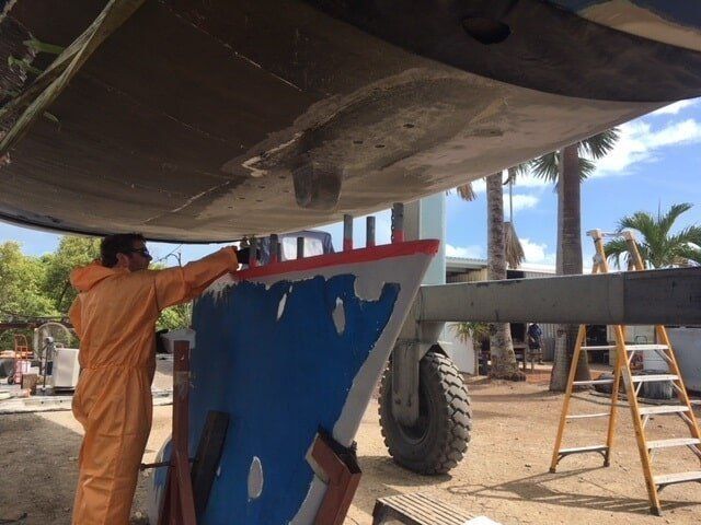 A Man In An Orange Suit Is Working On A Boat — Edge's Boatyard In Jubilee Pocket, QLD