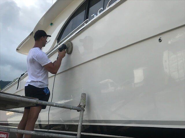 A Man Is Polishing The Side Of A Boat With A Machine — Edge's Boatyard In Jubilee Pocket, QLD
