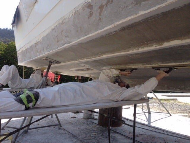 A Man Is Laying On A Table Under A Boat — Edge's Boatyard In Jubilee Pocket, QLD