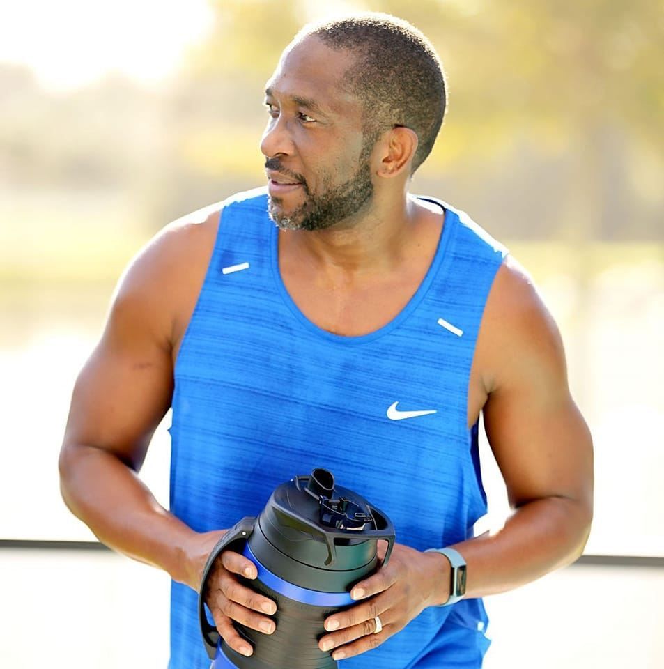 A man in a blue nike tank top is holding a bottle