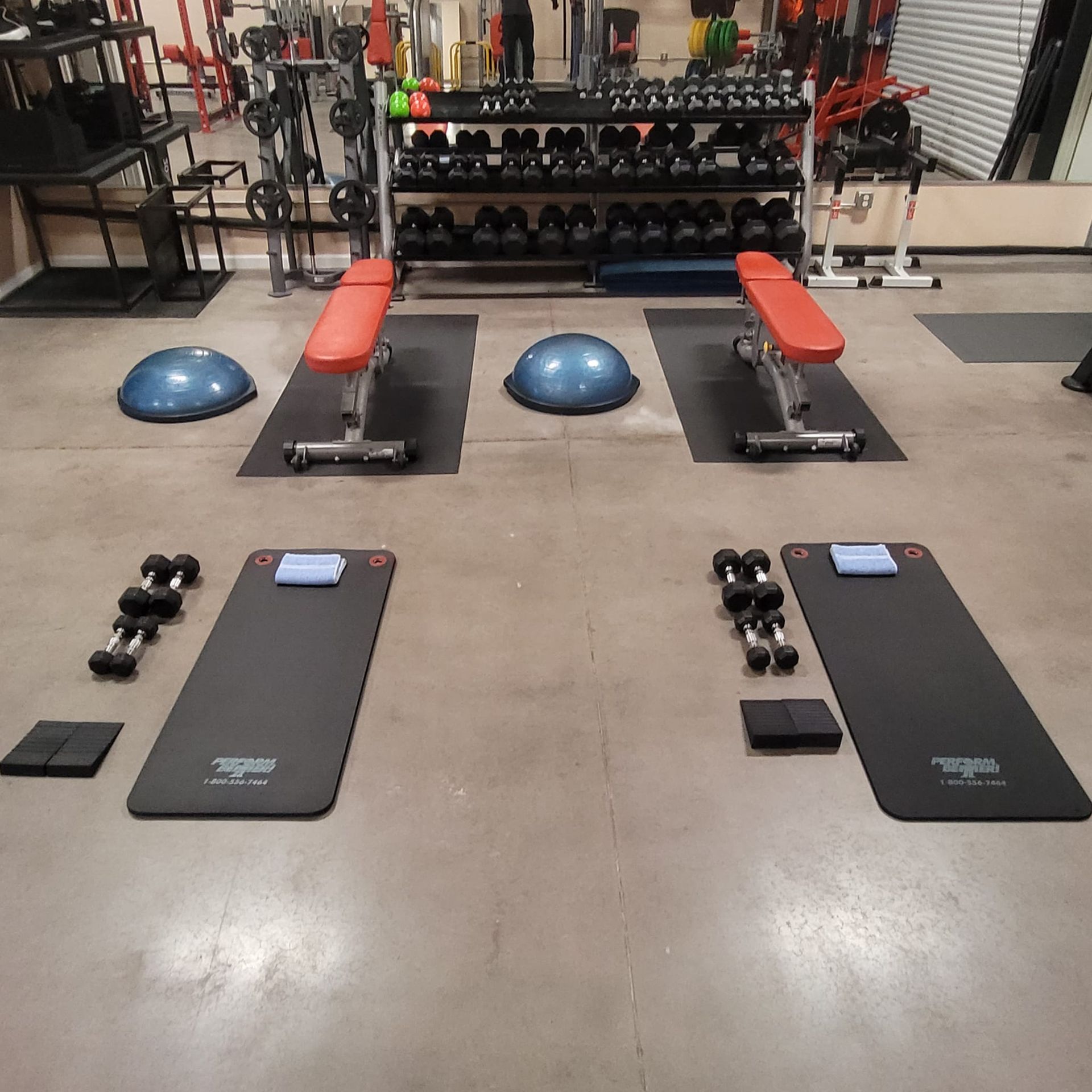 A gym with a bunch of exercise mats and dumbbells
