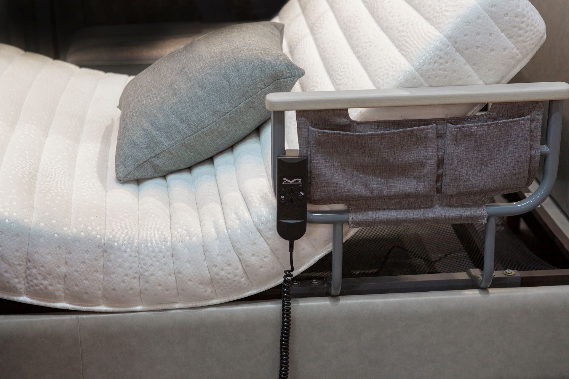 Letto regolabile con organizer da comodino, telecomando e cuscini.