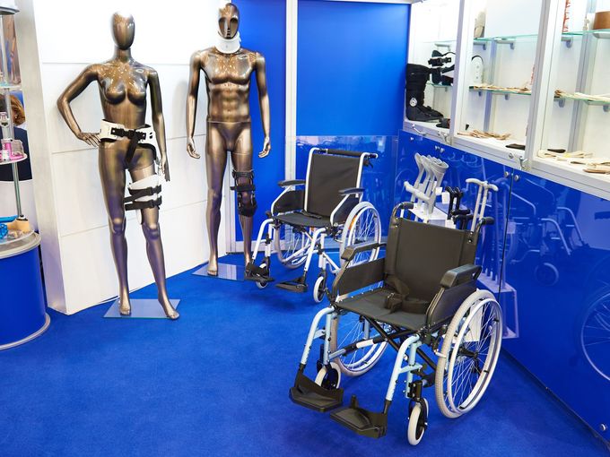 Sedie a rotelle esposte in un negozio di attrezzature mediche, insieme a manichini che mostrano accessori di supporto medico.