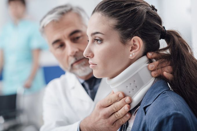 Un medico applica un collare cervicale a una donna in un ambiente medico.