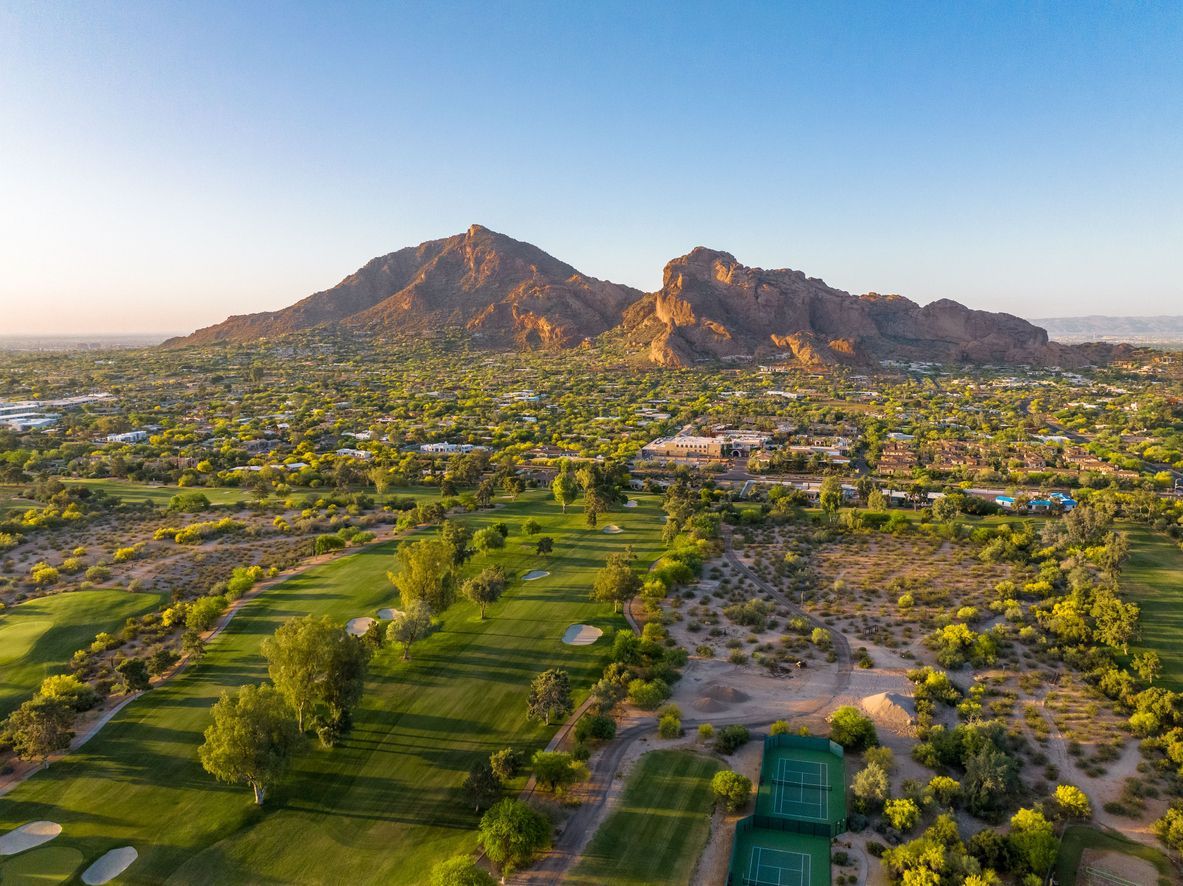 Flyover view of golf course with mountains in the background