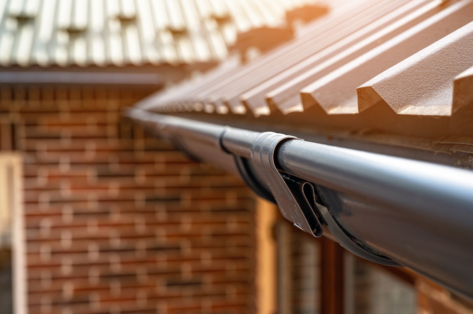 A close up of a gutter on the side of a brick building.