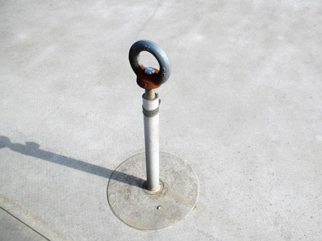 Metallring mit Pfosten, der in die Betonoberfläche eingelassen ist; wirft einen Schatten.