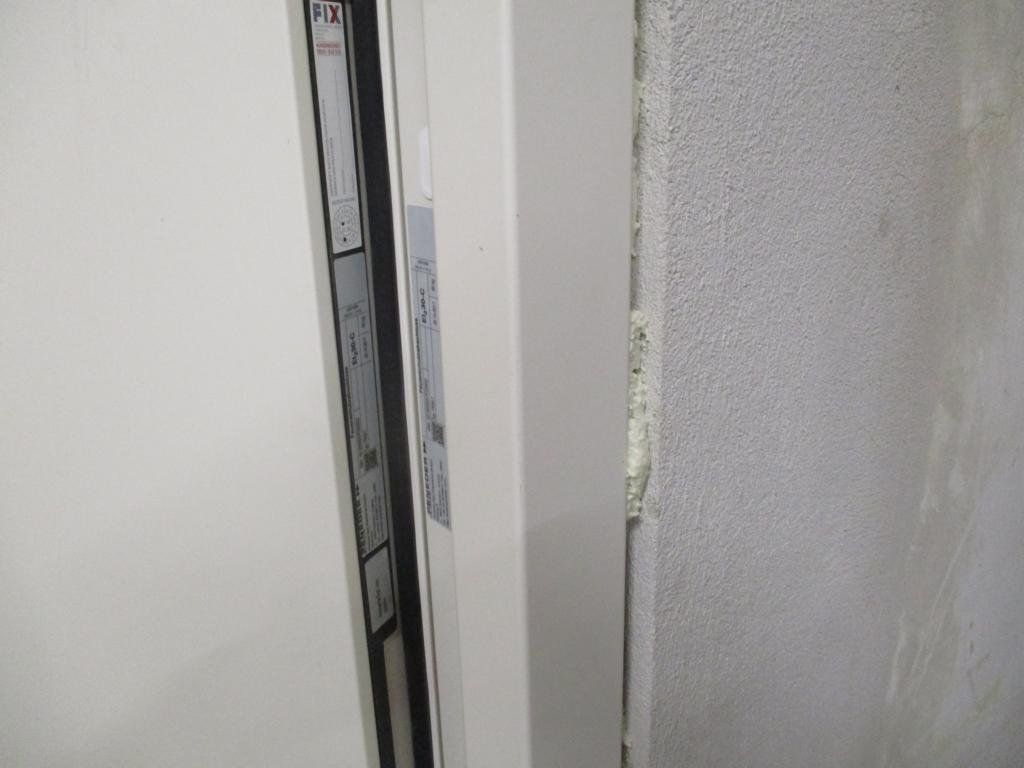 Weiße Tür leicht geöffnet neben einer strukturierten Wand.