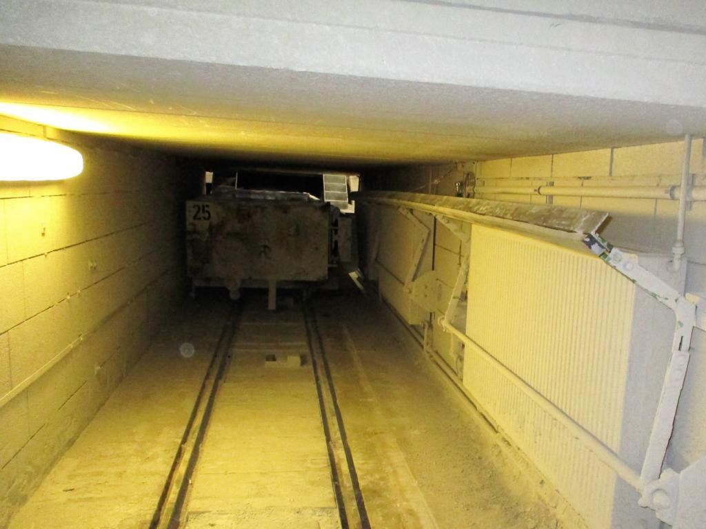 Eine Lore auf Schienen in einem schwach beleuchteten, engen Tunnel.
