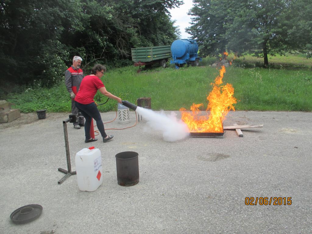 Eine Frau löscht während einer Übung im Freien ein Feuer mit einem Feuerlöscher.