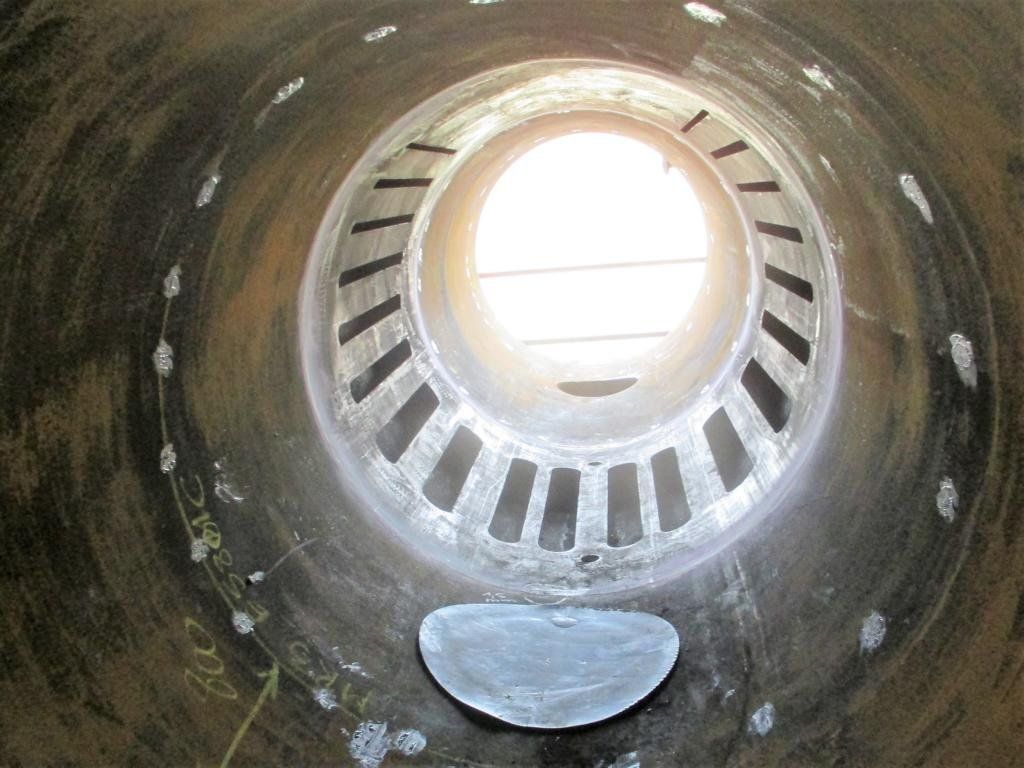 Innenansicht einer großen, zylindrischen Metallkonstruktion mit einem offenen, gitterartigen Abschnitt am Ende.