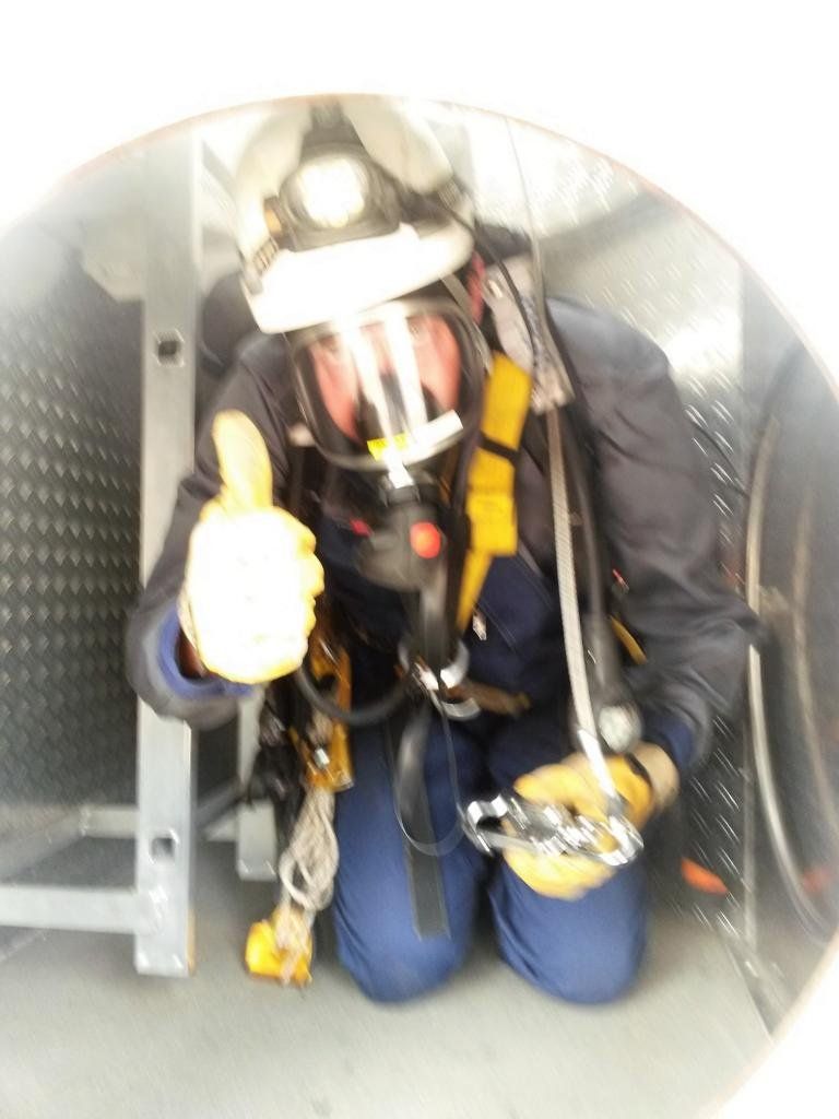 Feuerwehrmann in voller Schutzausrüstung, in einem Tunnel, zeigt den Daumen nach oben.