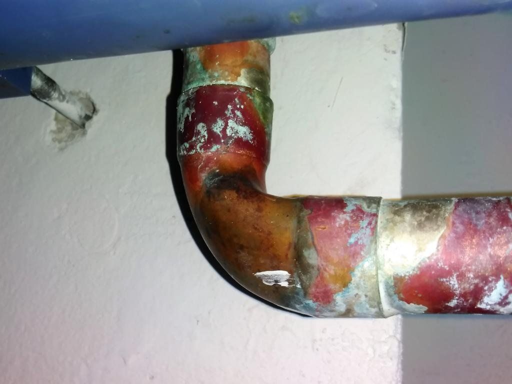 Kupferrohrbogen mit grüner und roter Korrosion.