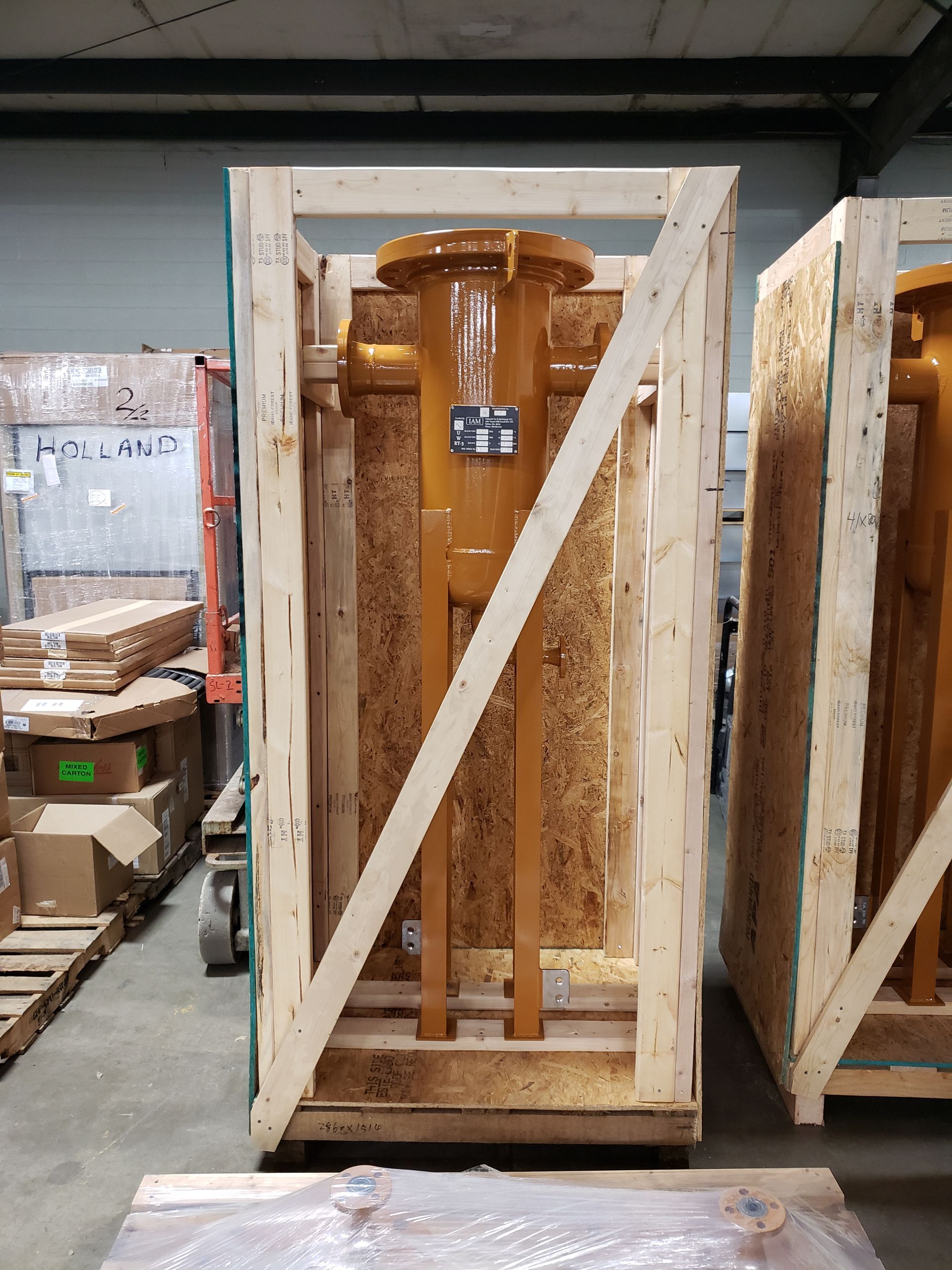 Tall, tan industrial equipment in a wooden crate, ready for shipping.