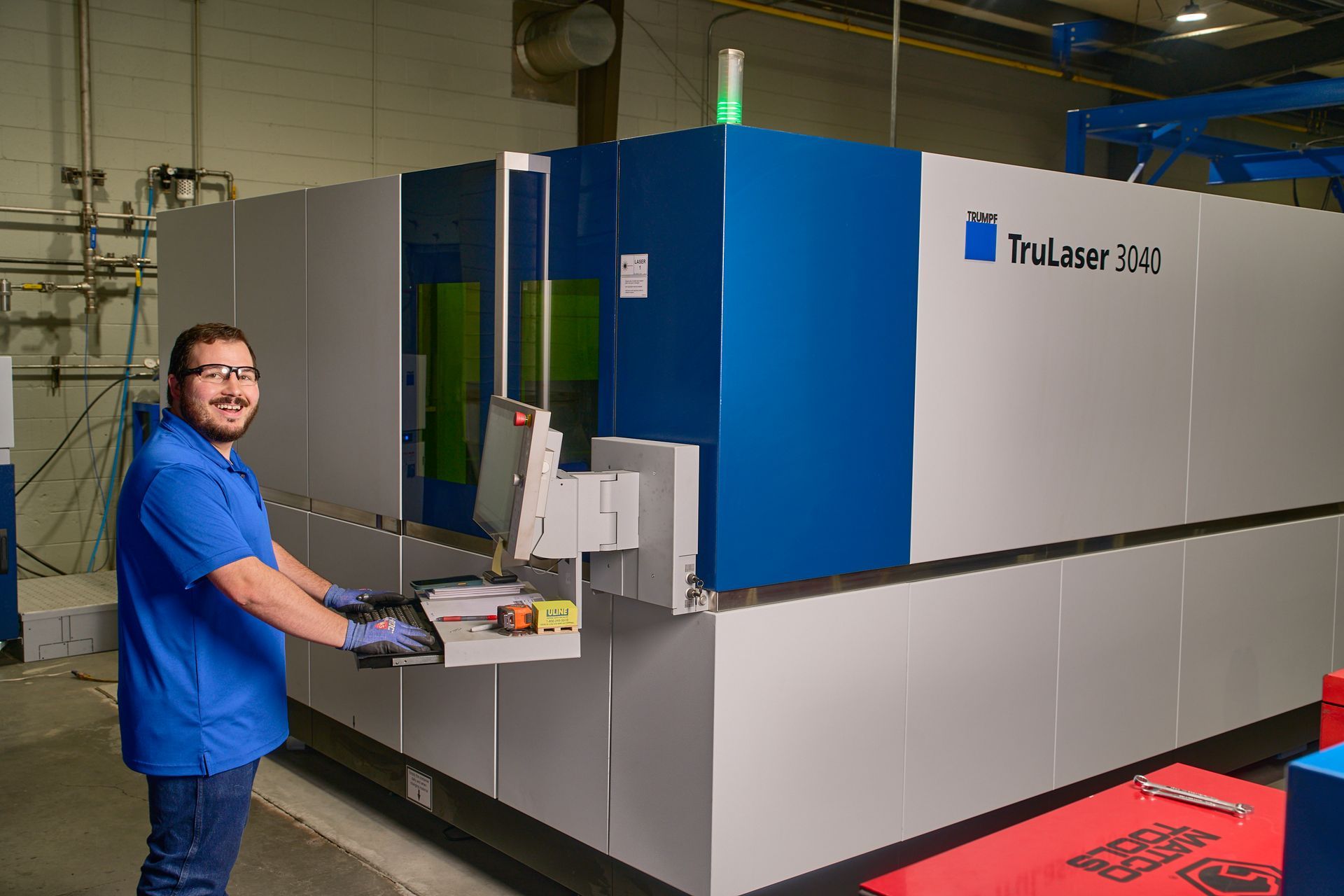 Man in blue shirt operating large industrial machine in a factory setting.