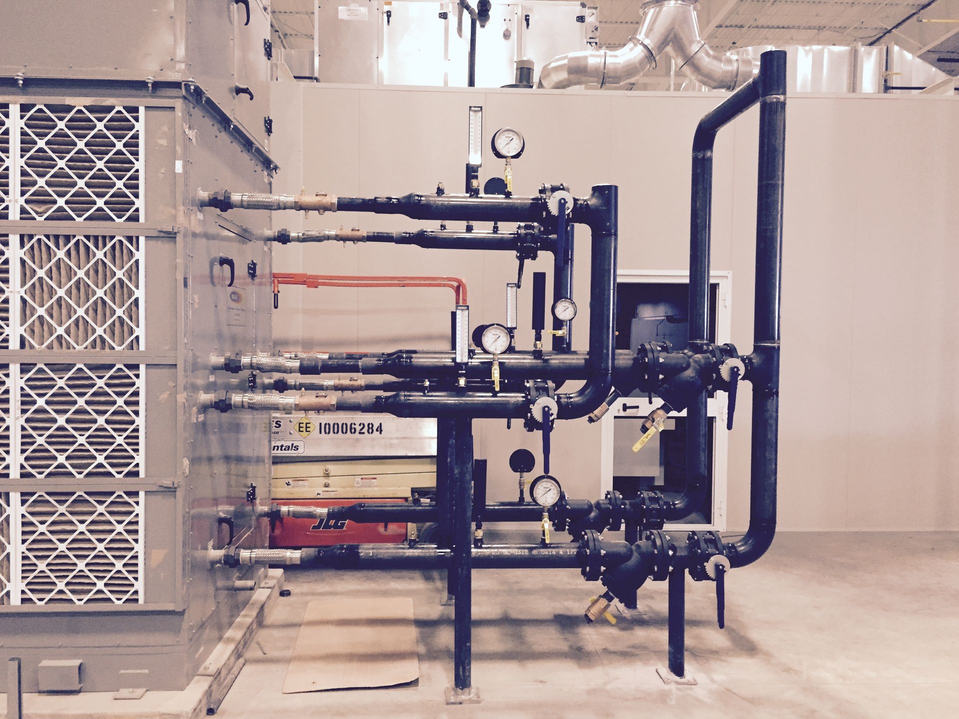 HVAC unit with pipes and gauges in a utility room.