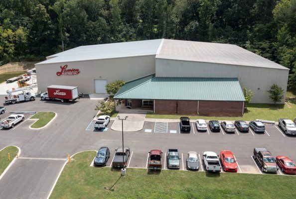 Warehouse building with parking lot and several vehicles.