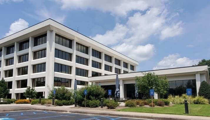 White office building with many windows, blue sky, and green grass.