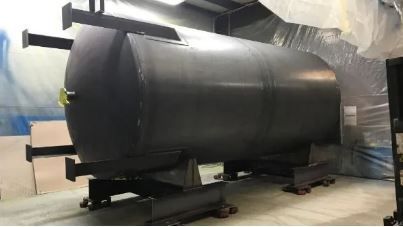 Black cylindrical tank on a black metal frame, inside a building.